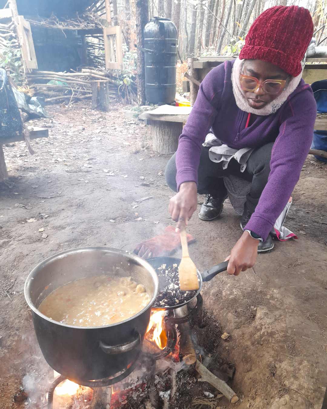 Woman wearing a hat cooking soup on the fire