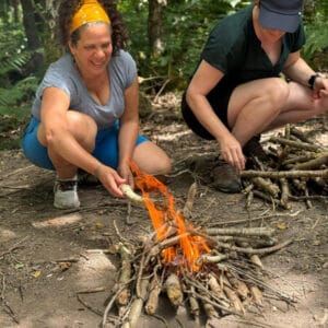 participant learning to cook on the fire in the woods