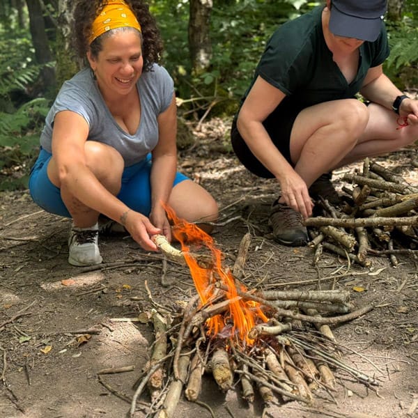 participant learning to cook on the fire in the woods